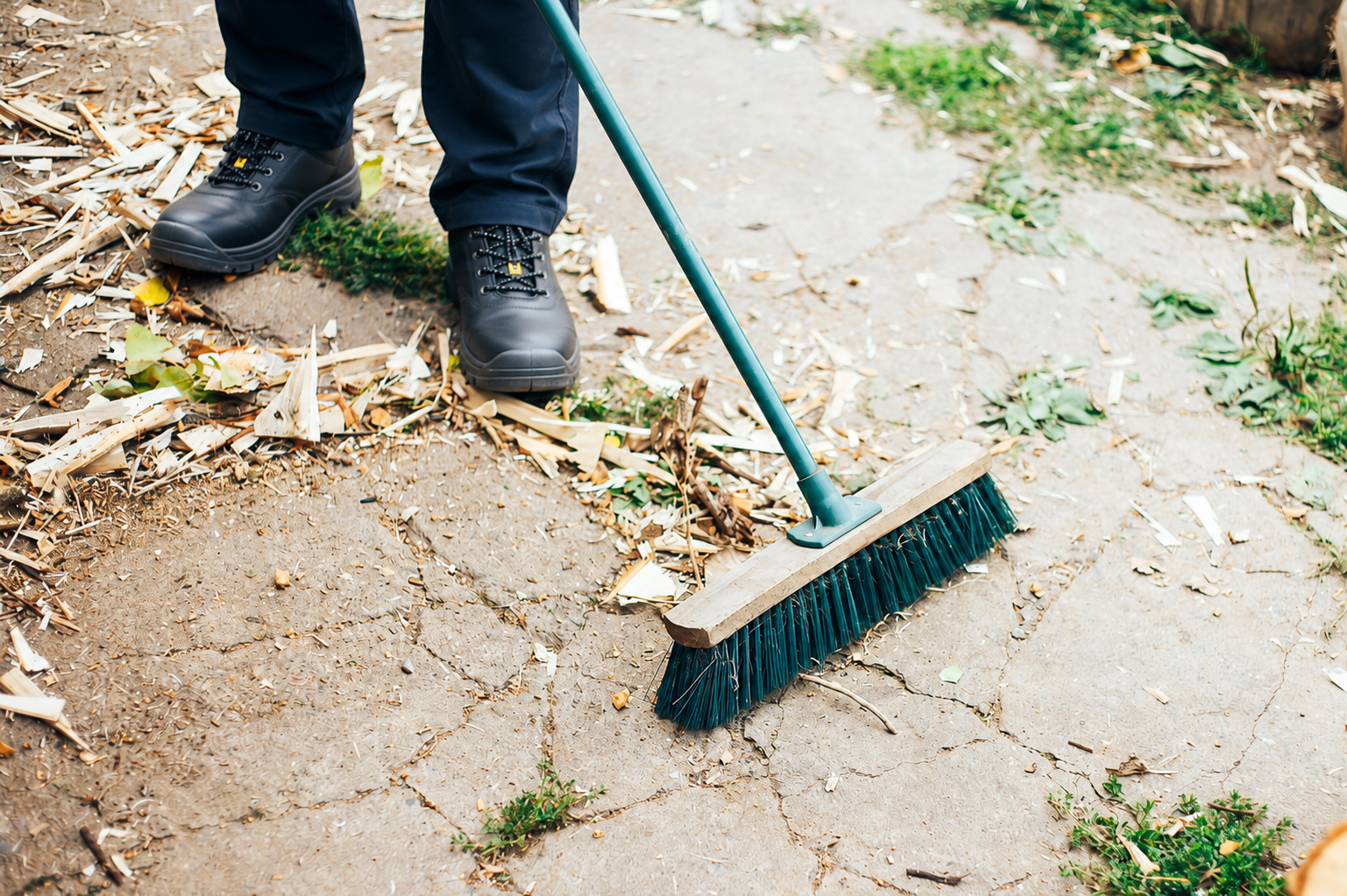 Personne balayant des feuilles dans une cour extérieure