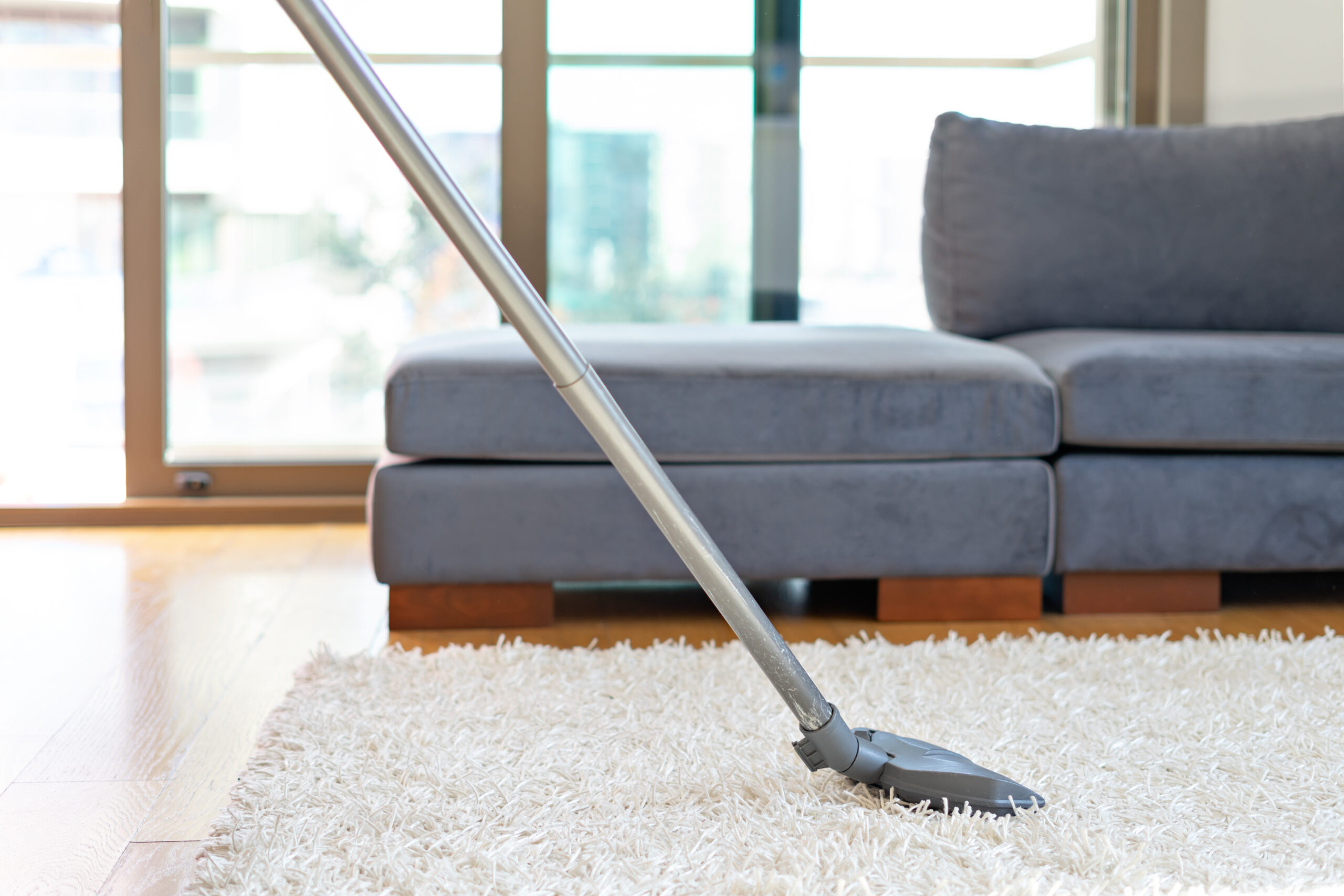 Aspirateur nettoyant tapis blanc dans salon moderne