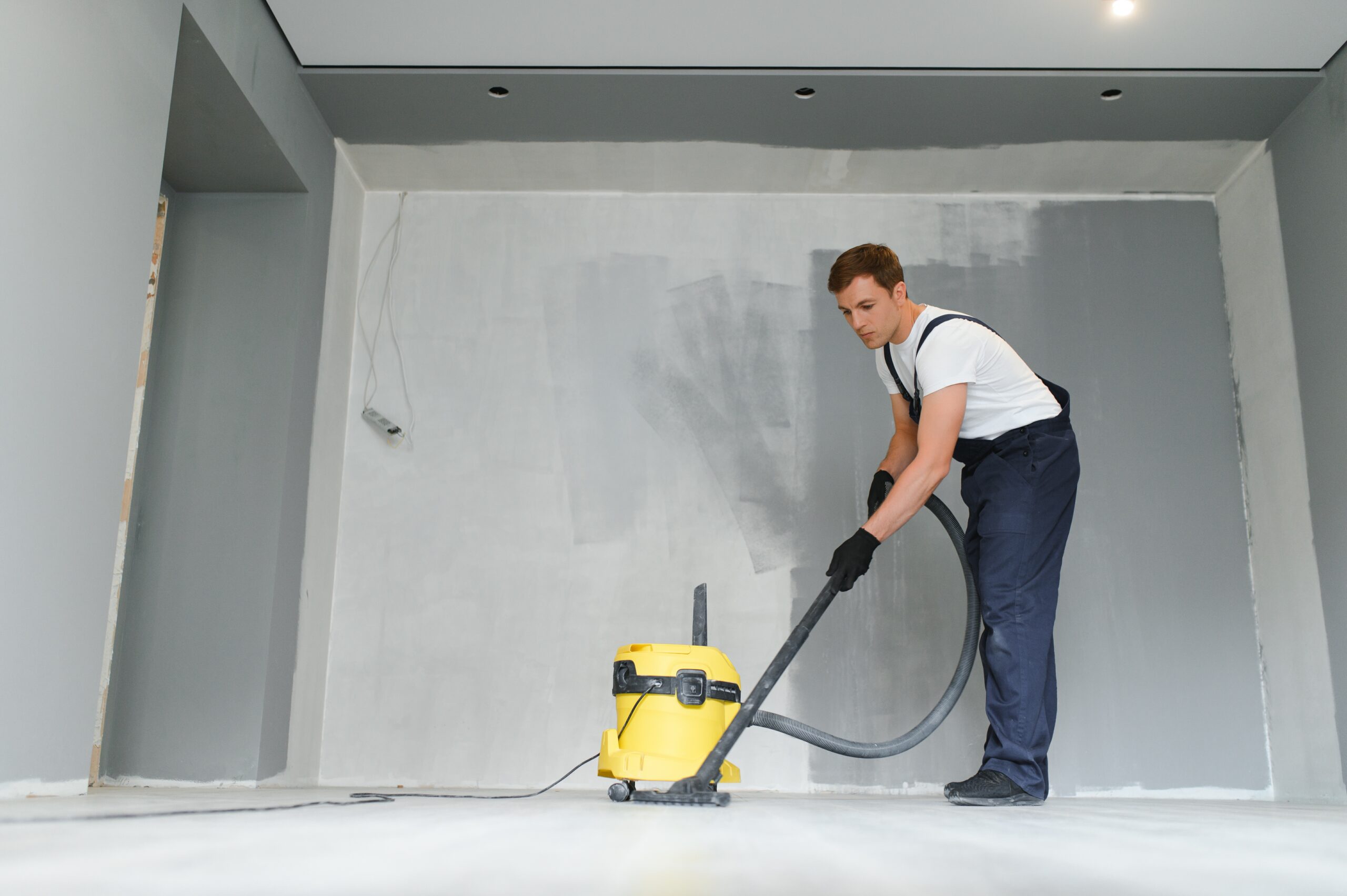 Homme aspirant sol dans pièce en rénovation