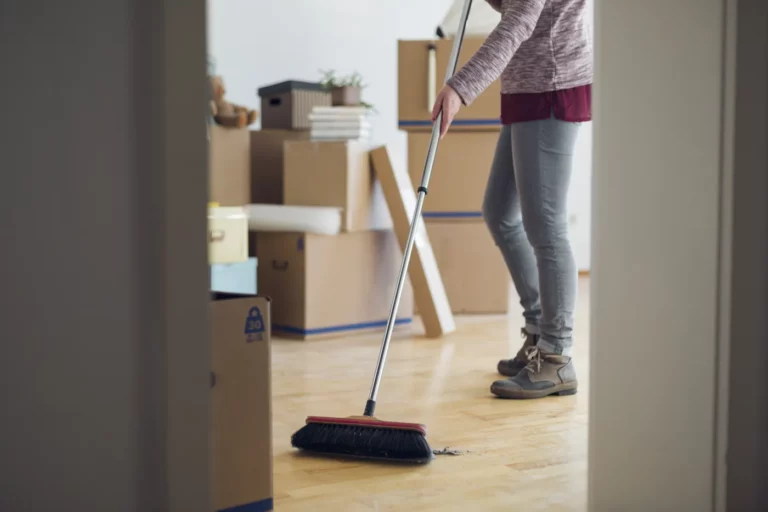 Femme balayant un parquet entre des cartons de déménagement