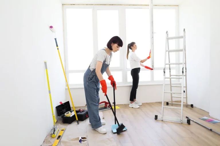 Deux femmes nettoyant une pièce aux murs blancs après des travaux de rénovation